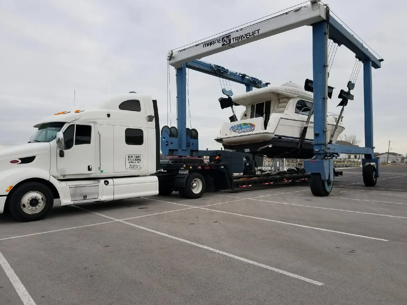 A boat being lifted by a travel lift at the yard